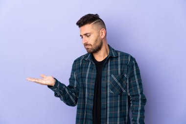 Mor arka planda izole edilmiş beyaz bir adam, kopyalama alanını şüpheyle tutuyor.