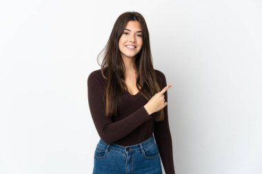 Beyaz arka planda izole edilmiş Brezilyalı genç bir kız bir ürün sunmak için kenarı işaret ediyor