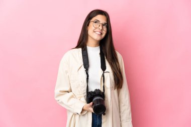 Genç fotoğrafçı Brezilyalı kız pembe arka planda izole edilmiş bir şekilde yukarı bakarken bir fikir düşünüyor.