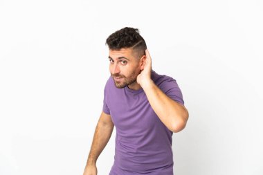 Beyaz arka planda izole edilmiş beyaz bir adam elini kulağına koyarak bir şeyler dinliyor.