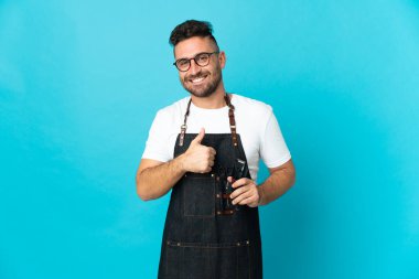 Önlüklü bir berber baş parmak hareketi yapıyor.