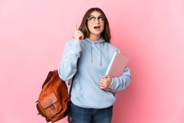 Pembe arka planda izole edilmiş genç bir bayan parmak kaldırmayı düşünüyor.