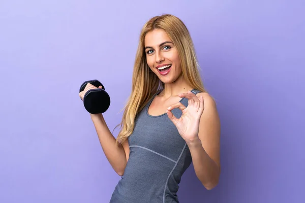 若いですブロンドスポーツ女性作る重量挙げ上の隔離された紫色の背景ショーOk Signとともに指 — ストック写真
