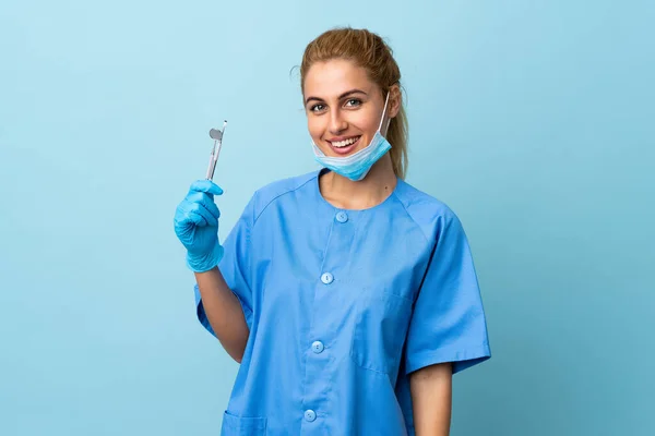 Junge Zahnärztin Hält Werkzeug Vor Isoliertem Blauen Hintergrund Und Lacht — Stockfoto