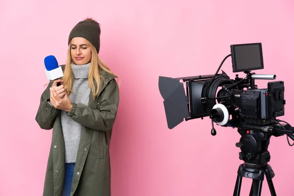 Reporter woman holding a microphone and reporting news over isolated pink background suffering from pain in hands