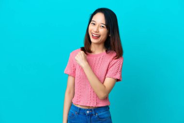 Genç Vietnamlı kadın mavi arka planda tek başına zaferi kutluyor.