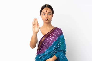 Beyaz arka planda izole edilmiş genç Hintli kadın dur hareketi yapıyor.