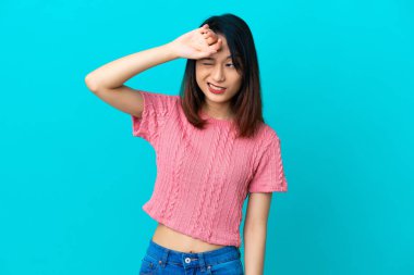 Genç Vietnamlı kadın yorgun ve hasta bir ifadeyle mavi arka planda izole edilmiş.