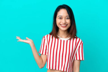 Mavi arka planda izole edilmiş genç Vietnamlı bir kadın, bir ilan vermek için avucunun içinde hayali bir fotokopi makinesi tutuyor.