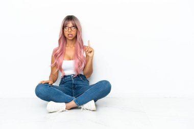 Pembe saçlı, beyaz arka planda soyutlanmış ve şaşırmış genç bir ırk kadını.