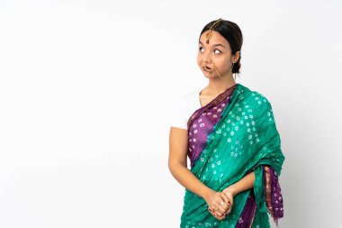 Beyaz arka planda izole edilmiş genç Hintli kadın şüpheli hareketler yapıyor.