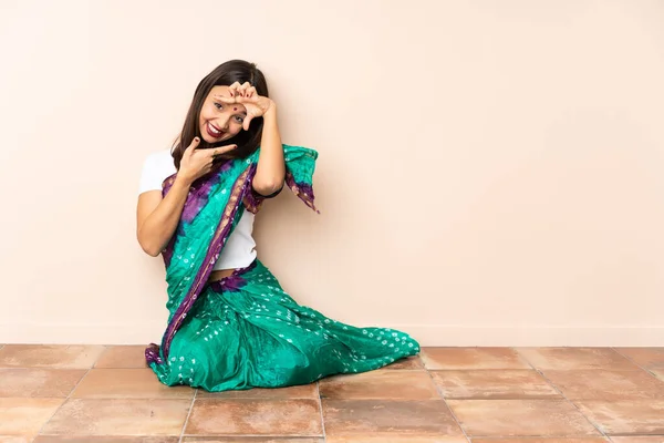 Young Indian woman sitting on the floor focusing face. Framing symbol