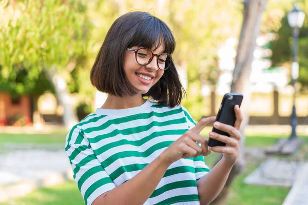 Jonge Brunette Vrouw Het Park Het Verzenden Van Een Bericht — Stockfoto