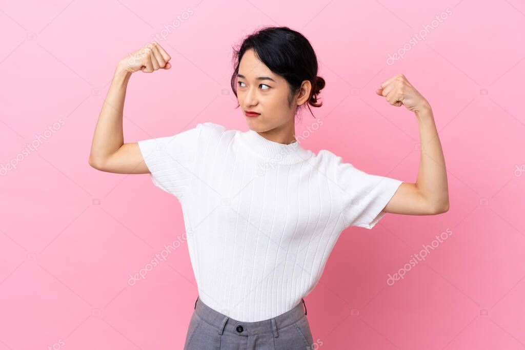 Young Vietnamese woman isolated on pink background doing strong gesture