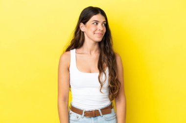 Sarı arka planda izole edilmiş genç beyaz kadın şüpheli hareketler yapıyor.