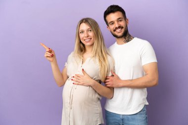 Genç çift hamile ve yan tarafı işaret ediyor.