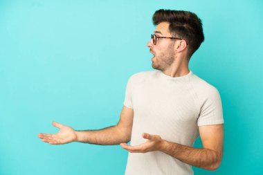 Mavi arka planda mahsur kalmış beyaz, yakışıklı genç bir adam.