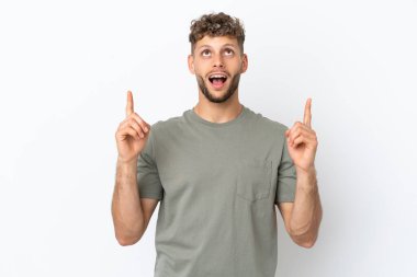 Beyaz arka planda izole edilmiş beyaz, yakışıklı genç adam şaşırmış ve yukarı bakıyor.