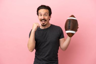 Pembe arka planda ragbi oynayan beyaz bir adam galibiyetini kutluyor.