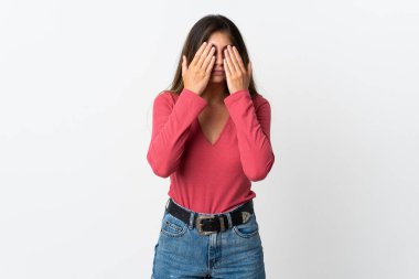 Beyaz arka planda izole edilmiş beyaz tenli genç bir kadın gözlerini elleriyle kapatıyor.