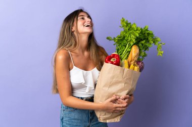 Alışveriş torbası tutan genç bir kadın gülüyor.