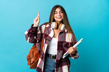 Mavi arka planda izole edilmiş genç bir bayan harika bir fikre işaret ediyor.