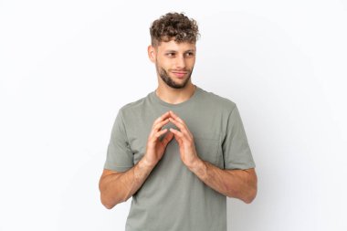 Beyaz arka planda izole edilmiş beyaz, yakışıklı bir adam bir şeyler planlıyor.