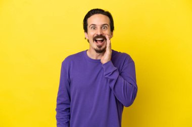Sarı arka planda izole edilmiş, şaşırmış ve şok olmuş genç bir beyaz adam.