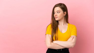 Pembe arka planda genç bir kız kollarını kavuşturuyor.