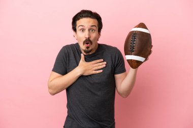 Pembe arka planda ragbi oynayan genç beyaz adam şaşırdı ve şaşırdı.