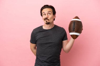 Genç, beyaz bir adam pembe arka planda izole edilmiş bir şekilde ragbi oynuyor.