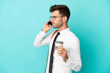 İş adamı izole edilmiş arka planda kahve ve cep telefonu tutuyor.