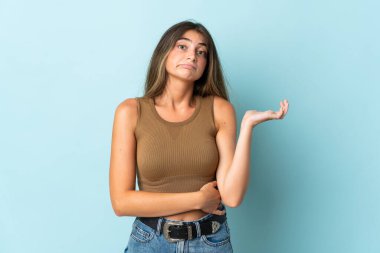 Kafkasyalı genç bir kadın mavi arka planda izole edilmiş. Şüpheleri var.