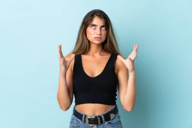 Mavi arka planda izole edilmiş genç beyaz kadın bunalımda.