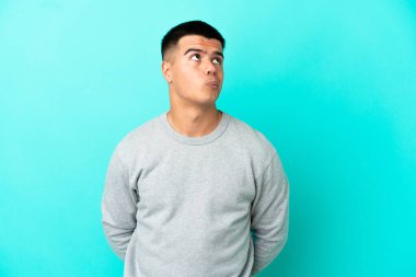 Soyutlanmış mavi arka planda genç yakışıklı bir adam.