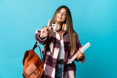 Mavi arka planda izole edilmiş genç bir bayan parmağını kaldırıyor ve gösteriyor.