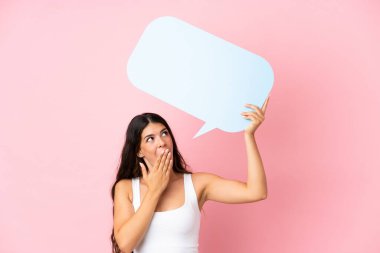 Pembe arka planda izole edilmiş beyaz bir kadın elinde şaşırmış bir ifadeyle boş bir konuşma balonu tutuyor.