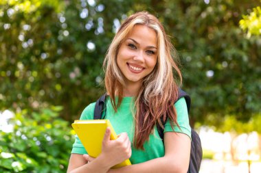Dışarıda elinde bir defter tutan genç bir kız öğrenci.