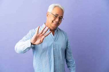 Mor arka planda izole edilmiş orta yaşlı Brezilyalı adam mutlu ve parmakları olan dört kişi sayıyor.