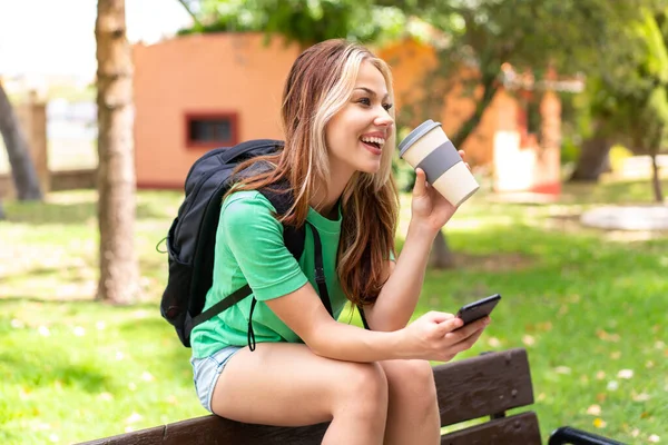 Giovane Studentessa All Aperto Utilizzando Telefono Cellulare Tenendo Caffè Asporto — Foto Stock