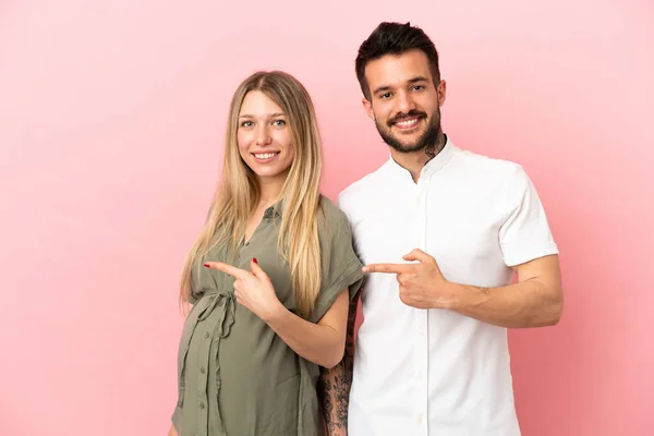 Gravid Kvinna Och Man Över Isolerad Rosa Bakgrund Peka Finger — Stockfoto