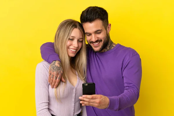 Pareja Joven Sobre Fondo Amarillo Aislado Enviando Mensaje Correo Electrónico —  Fotos de Stock