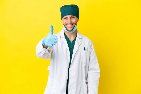 Χειρούργος Ξανθός Άντρας Πράσινη Στολή Απομονωμένος Κίτρινο Φόντο Τους Αντίχειρες — Φωτογραφία Αρχείου
