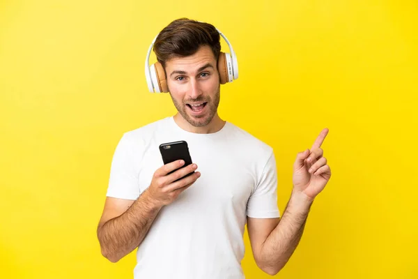 Young Caucasian Handsome Man Isolated Yellow Background Listening Music Mobile — Stock Photo, Image