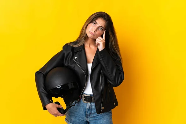 黄色の背景に隔離されたオートバイのヘルメットを持っている女性は考えを考える — ストック写真