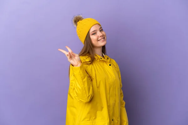 Chica Adolescente Con Abrigo Impermeable Sobre Fondo Púrpura Aislado Sonriendo —  Fotos de Stock