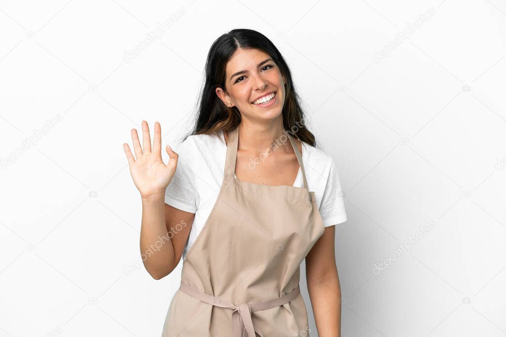 Restaurant waiter over isolated white background saluting with hand with happy expression