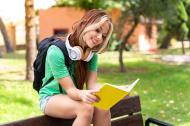 Dışarıda elinde bir defter tutan genç bir kız öğrenci.