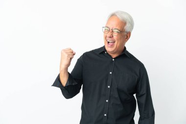 Orta yaşlı Brezilyalı bir adam beyaz bir arkaplanda zaferi kutluyor.