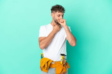 Genç elektrikçi, yeşil arka planda izole edilmiş sarışın adam öksürükten muzdarip ve kötü hissediyor.